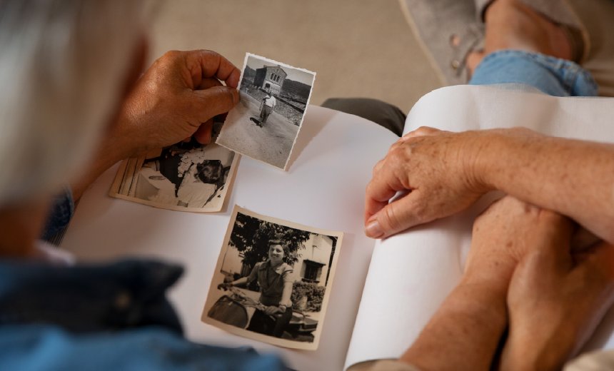 Adulto mayor revisando fotografías antiguas que representan la memoria y el legado emocional en vida.